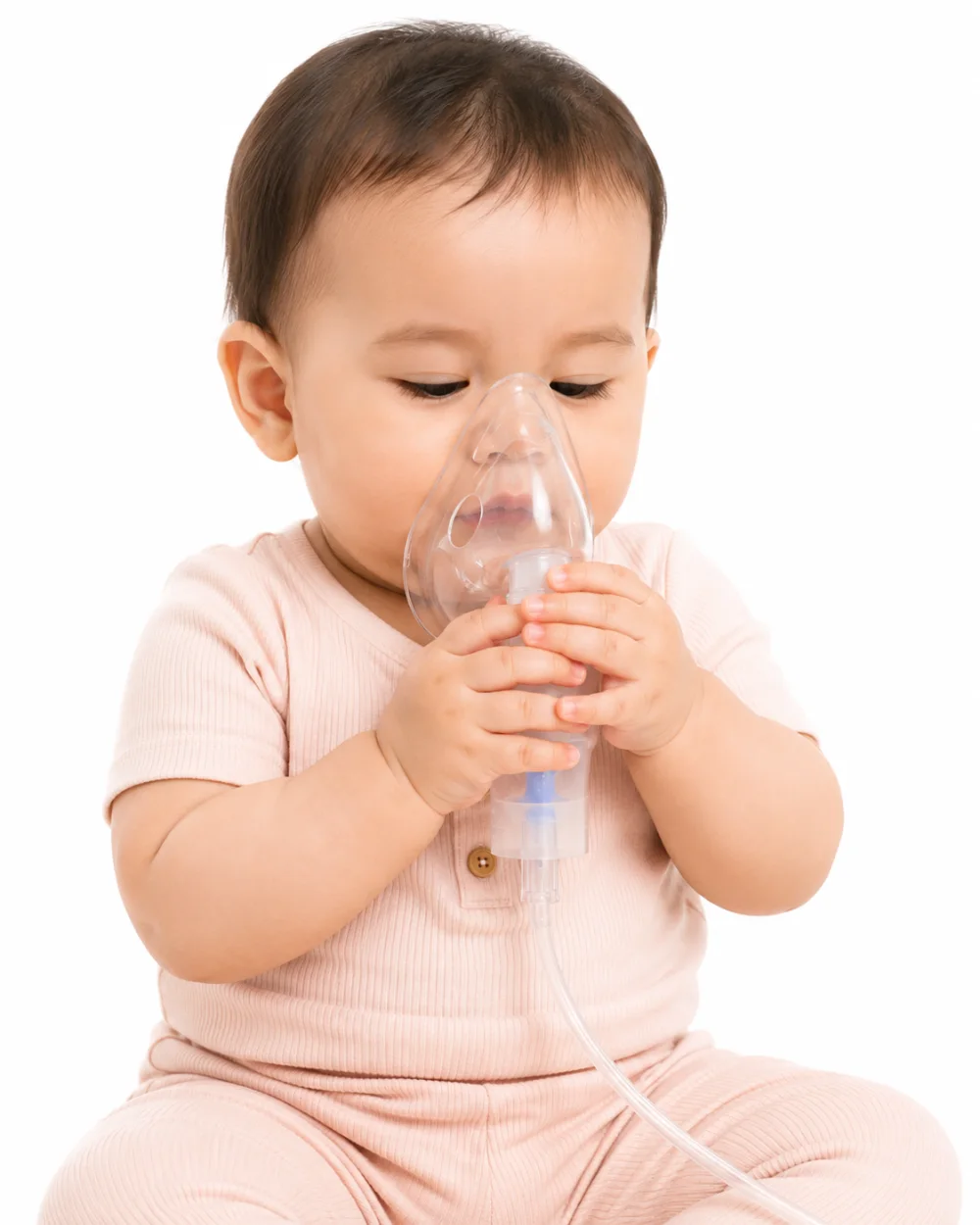 Bayi memegang topeng nebulizer